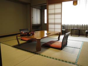 sala de estar con mesa de madera y sillas en Sakaeya Hotel en Tendo