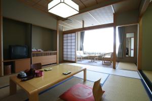 ein Wohnzimmer mit einem Tisch und einem TV in der Unterkunft Sakaeya Hotel in Tendō