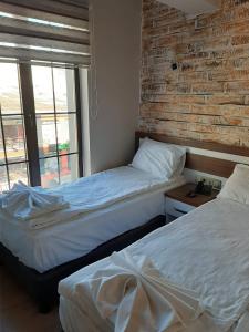two beds in a room with a brick wall at Hotel kafkasya in Kars
