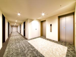 an empty corridor of an office building with white doors at Hotel Livemax Premium Nagano Ekimae in Nagano