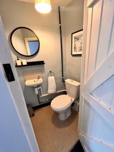 een badkamer met een toilet, een wastafel en een spiegel bij The Snuggery Cottage in Taunton