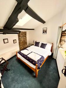 The Snuggery Cottage في تونتون: غرفة نوم بسرير وجدار حجري