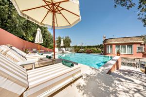 a swimming pool with an umbrella and lounge chairs and a swimming pool at Casa dei fiori in Corfu