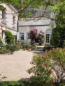 duży biały dom z kwiatami przed nim w obiekcie Les Troglos de la Tufolière w mieście Rochecorbon