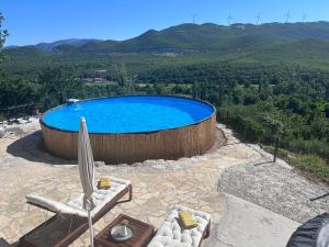 a large swimming pool with an umbrella and a chair at Holiday Home - Boanerges Heritage in Blato na Cetini