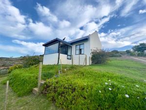 ein kleines Haus auf einer grünen Wiese in der Unterkunft Riverdance Cottage in Malgas