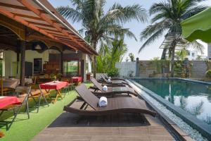 un complejo con piscina con sillas y mesa en RAON Hoi An - STAY 24H, en Hoi An