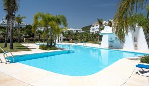 ein großer Pool mit Palmen und Gebäuden in der Unterkunft Alcazaba Lagoon 2425 Luxury private beach in Estepona