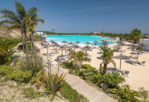 einen Strand mit Sonnenschirmen und Stühlen sowie einen Pool in der Unterkunft Alcazaba Lagoon 2425 Luxury private beach in Estepona