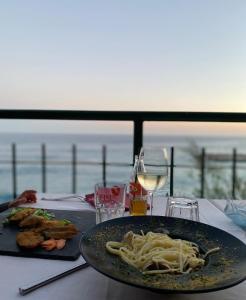 a table with a plate of pasta and a glass of wine at Casa Mia Bogliasco Mare & Centro in Bogliasco