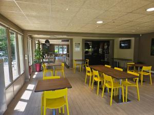 ein Restaurant mit Holztischen und gelben Stühlen in der Unterkunft Campanile Deauville Saint-Arnoult in Deauville
