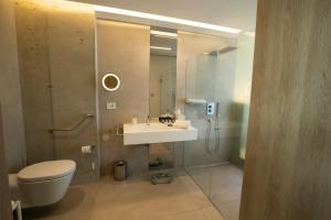 a bathroom with a sink and a toilet and a mirror at Posia Retreat & Spa UNA Esperienze in San Foca