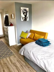 um quarto com uma cama e um sofá amarelo em Elkstone Studio Private Hottub Pet Friendly em Malvern Link