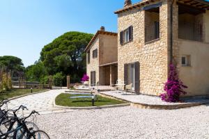 un edificio de piedra con flores púrpuras delante de él en Dimora La Fiumara, en Marina di Grosseto