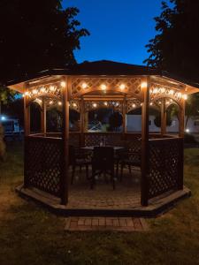 a gazebo with a table and lights at night at Dom Wypoczynkowy Olivia in Darłówko