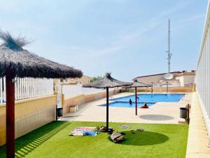 a swimming pool withiki umbrellas and a swimming pool at Casa Natura Sunset Beach in Gran Alacant