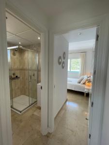 La Duquesa Appartement 507 في مانيلفا: حمام مع دش زجاجي وغرفة نوم