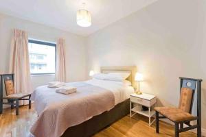 a bedroom with a bed and two chairs and a window at Luxury Two Bedroom Apt in Dublin in Dublin