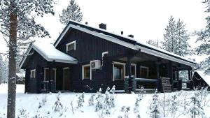 a log cabin in the snow with snow covered trees at Jänkäkolo Holiday Home in Pyhätunturi
