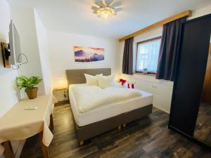 Schlafzimmer mit einem Bett, einem Tisch und einem Fenster in der Unterkunft Pension Jagerhof - Sommercard Inkl - 5 Min zum Hochzeiger in Jerzens