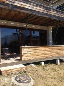 a house with a wooden porch with a bench on it at Appartement charme CHAMROUSSE in Chamrousse
