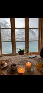 拉姆貝格的住宿－Rorbu Vestersia i Skjelfjord，一张桌子,上面有两把蜡烛和一个雪窗