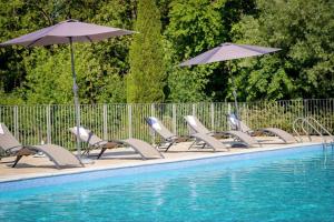 - une rangée de chaises et de parasols à côté de la piscine dans l'établissement La Résidence du Château de Jouarres, à Azille
