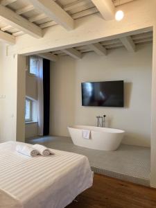 baño grande con bañera y TV en la pared en Urbino Apartment - Torricini View, en Urbino