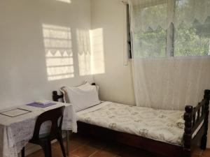 um pequeno quarto com uma cama, uma mesa e uma janela em Eua Accommodation em ‘Ohonua