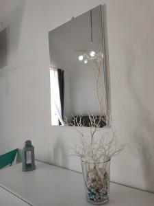 a vase with rocks and branches in front of a mirror at La casa di Nonna Rosa in Procida