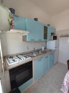 La casa di Nonna Rosa في بروسيدا: مطبخ مع دواليب زرقاء ومغسلة وموقد