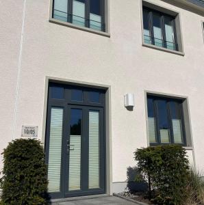 a white building with a door and two windows at Ferienwohnung "Julie" - Haus Alando in Prora
