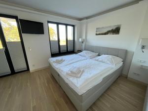 a bedroom with a large white bed with two windows at Ferienwohnung "Julie" - Haus Alando in Prora +21 photos
