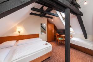 a attic bedroom with two beds and a desk at Novum Hotel Ahl Meerkatzen Köln Altstadt in Cologne