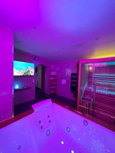 a purple room with a tub and a tv at La Suite Sun Set in Tremblay-En-France