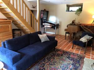 a living room with a blue couch and a piano at Le Moulin de la Farge B&B in Saint-Moreil