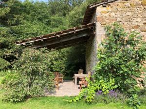um jardim com uma mesa de madeira e uma parede de pedra em Le Moulin de la Farge B&B em Saint-Moreil