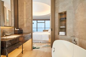 a bathroom with a tub and a bedroom with a bed at The Westin Wenzhou in Wenzhou