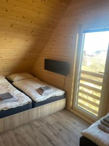 2 Betten in einem Holzzimmer mit Fenster in der Unterkunft Rezortík Gerlachov CHATA 1 in Gerlachov