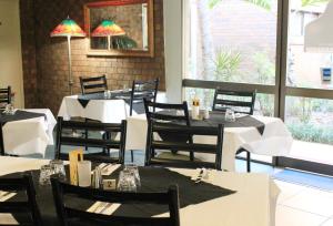 une salle à manger avec des tables blanches et des chaises noires dans l'établissement Best Western Ipswich, à Ipswich