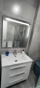 y baño con lavabo blanco y espejo. en Coqueto apartamento en La Barrosa de un dormitorio, en Chiclana de la Frontera