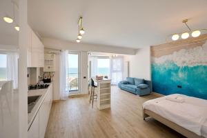 a bedroom with a bed and a kitchen with a blue couch at Sea-esta Studio in Infinity Beach Resort in Mamaia