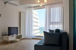 a living room with a blue couch and a large window at Sea-esta Studio in Infinity Beach Resort in Mamaia
