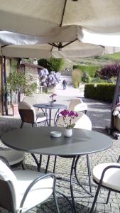 2 Tische und Stühle mit Blumen auf der Terrasse in der Unterkunft Trattoria Del Bivio in Cerretto Langhe