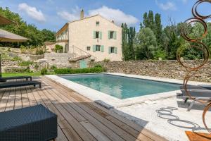 a villa with a swimming pool in front of a house at Le Moulin Dumas in Grignan