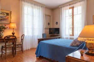 a bedroom with a blue bed and a desk and windows at La Maison de Mireille in Le Puy en Velay