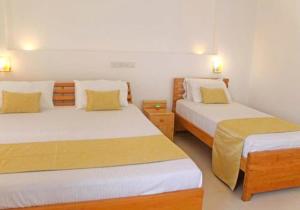um quarto com 2 camas e almofadas amarelas em Apna Colombo em Nawala