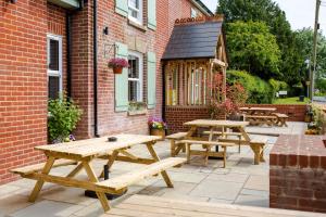 un groupe de tables de pique-nique à l'extérieur d'un bâtiment en briques dans l'établissement Woodfalls Inn, à Redlynch