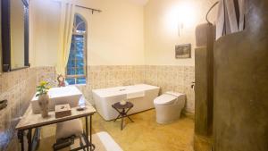 een badkamer met een bad, een toilet en een wastafel bij Chara Africa Hotel in Usa River