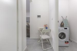 a laundry room with a washing machine and a chair at Borgo Panigale Viola Apartment in Bologna